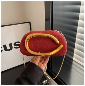 Close-up of red woven clutch bag with large gold semi-circular handle and chain strap