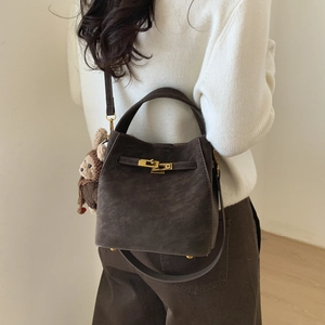 Brown bucket bag with plush monkey charm shown on model for size perspective