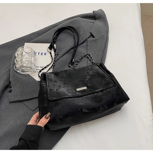 Gros plan d'un sac à bandoulière rétro noir avec texture mate et chaîne métallique