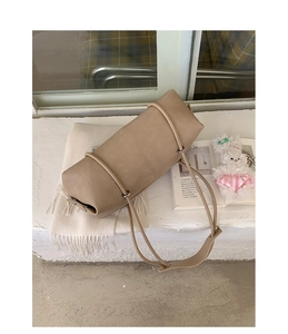 Detail view of a beige minimalist leather bowling bag with soft texture and long shoulder strap