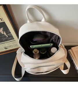 White faux leather backpack showing spacious interior with cosmetics and accessories