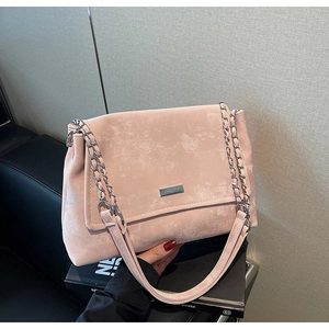 Détail de la texture en daim rose mat avec logo argenté et bandoulière en chaîne de métal