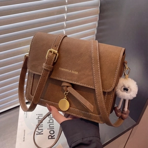 Detail of brown vintage crossbody bag with fashion gold text and plush charm