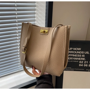 Détail d'un sac seau beige en cuir PU grainé avec fermoir rotatif en métal doré élégant