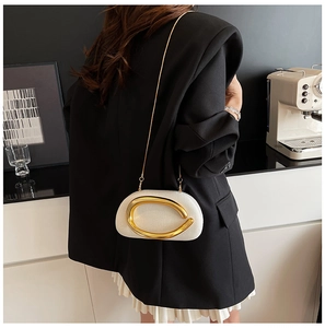 Close-up of white woven shoulder bag with large gold C-handle and chain strap on model