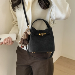 Detailed shot of black bucket bag featuring golden twist lock and a cute bear pendant