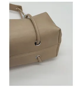 Detail of round rope shoulder strap and silver metal eyelets on beige leather tote bag