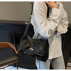 Détail d'un grand sac cabas noir vintage avec bandoulière chaîne et plaque métallique