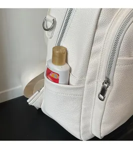 Detail of white lychee leather backpack side pocket with metallic zipper and D-ring