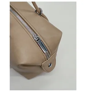 Detailed macro view of the smooth silver metal zipper on a beige leather tote bag