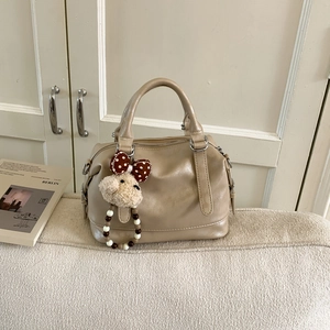 Detailed close-up of a khaki Boston tote bag with a cute plush puppy charm accessory