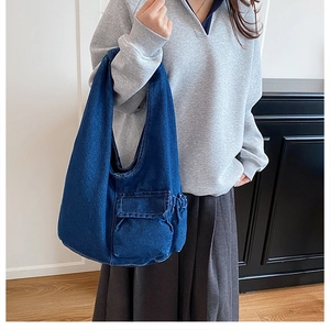 Detail view of large indigo denim tote bag with functional flap pocket and side pockets