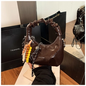 Detailed shot of coffee brown patent leather bag with pleated handle and charm details