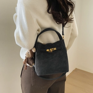 Detail of black matte bucket bag with gold buckle and cute brown bear keychain accessory