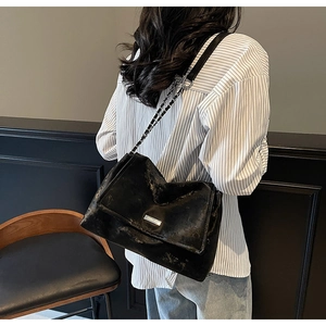 Vue détaillée d'un grand sac cabas noir avec bandoulière chaîne porté par un mannequin