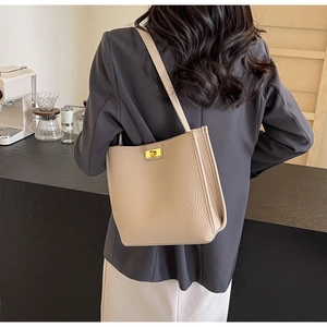 Détail du sac à bandoulière beige avec fermoir métallique doré et texture cuir grainé