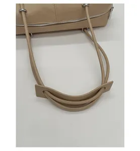 Detail of beige Boston bag showing the wide padded shoulder strap and silver zipper closure