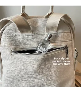 Detail view of anti-theft back zipper pocket on beige pebbled leather backpack