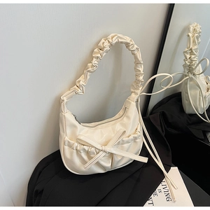 Detail of cream white pleated bow handbag with mirror reflection showing side profile