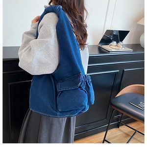 Detail showing the multi-pocket structure and denim fabric texture of the blue tote bag
