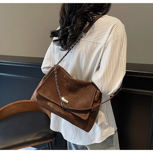Détail du sac cabas marron vintage avec plaque logo et bandoulière en chaîne