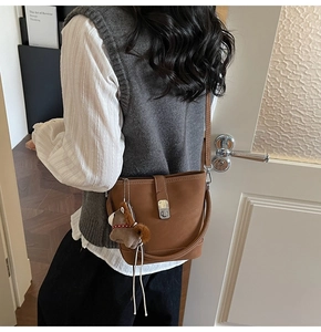 Detail of dark brown leather bucket bag with silver clasp and a pony charm accessory