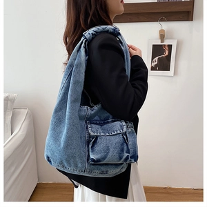 Side view of a vintage denim hobo shoulder bag with large front pocket on model