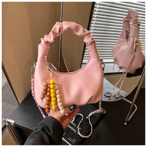 Detail of pink dumpling bag with pleated texture, wooden beads, and metal chain strap