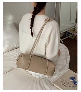 Detailed view of beige minimalist bowling shoulder bag with vertical stitching and thin straps