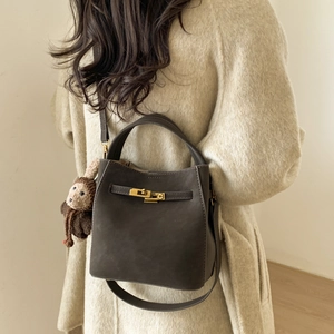 Detail of dark brown matte bucket bag with gold twist lock and a cute plush monkey charm