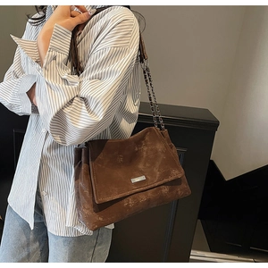 Détail du sac à bandoulière marron vintage avec rabat et logo en métal sur un modèle
