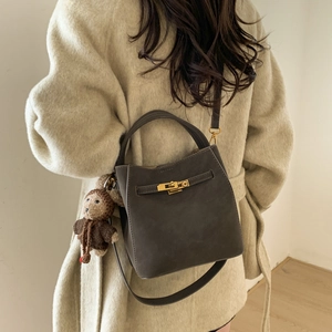 Deep grey matte bucket bag featuring gold metal lock and brown monkey charm detail