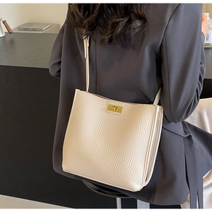 Détail du sac seau en cuir grainé crème avec fermoir rotatif doré et bandoulière