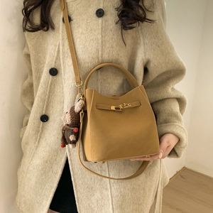 Ginger bucket bag in matte leather with turn-lock clasp and bear charm on a crossbody strap