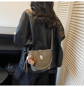 Detail of dark green bucket bag with leather straps and a brown horse plush charm