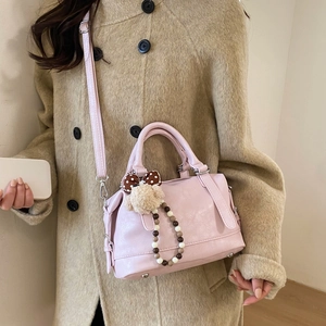 Close-up of pink leather tote bag featuring cute plush bear charm and handle detail