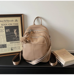 Detail of khaki pebbled leather backpack with silver zippers and woven patterned strap