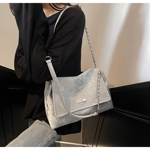 Détail du cabas gris clair présentant une texture en cuir mat et une chaîne argentée