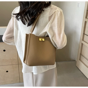 Dettaglio borsa a secchiello in pelle martellata color cammello scuro con chiusura d'oro