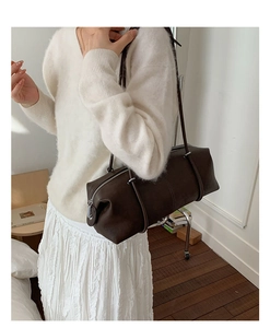 Detailed view of dark brown leather cylinder shoulder bag with minimalist zipper and long strap