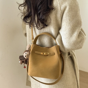 Detail of yellow bucket bag with metal buckle and rabbit charm on wool coat
