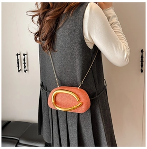 Detail view of stylish orange textured acrylic bag with gold buckle on shoulder