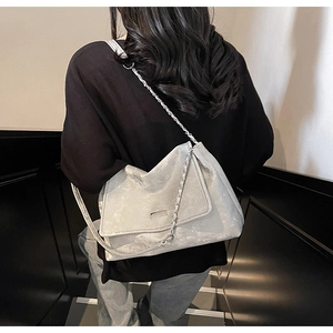 Détail du sac gris argenté avec texture métallique froissée et bandoulière chaîne