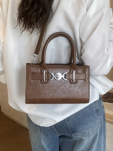 Vintage brown leather crossbody handbag with silver heart buckle shown on model