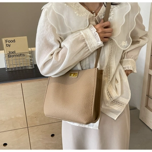 Detail of lychee textured bucket bag with golden square twist lock and shoulder strap