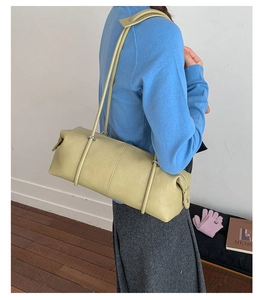 Close-up of light green leather cylindrical shoulder bag with smooth texture and strap detail