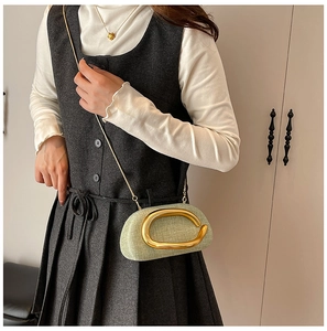 Detail of light green woven handbag featuring a large golden C-ring and fine chain strap