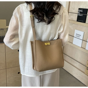 Vue arrière d'un mannequin portant un sac cabas en cuir grainé marron clair à fermoir doré