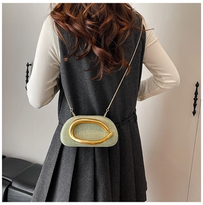Detail of green linen textured crossbody bag with oversized gold ring and chain strap