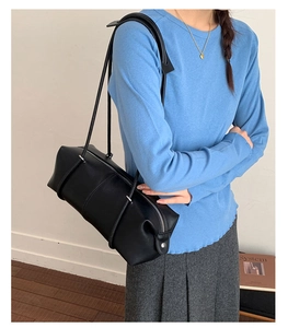 Minimalist black leather bowling shoulder bag shown on model with long straps